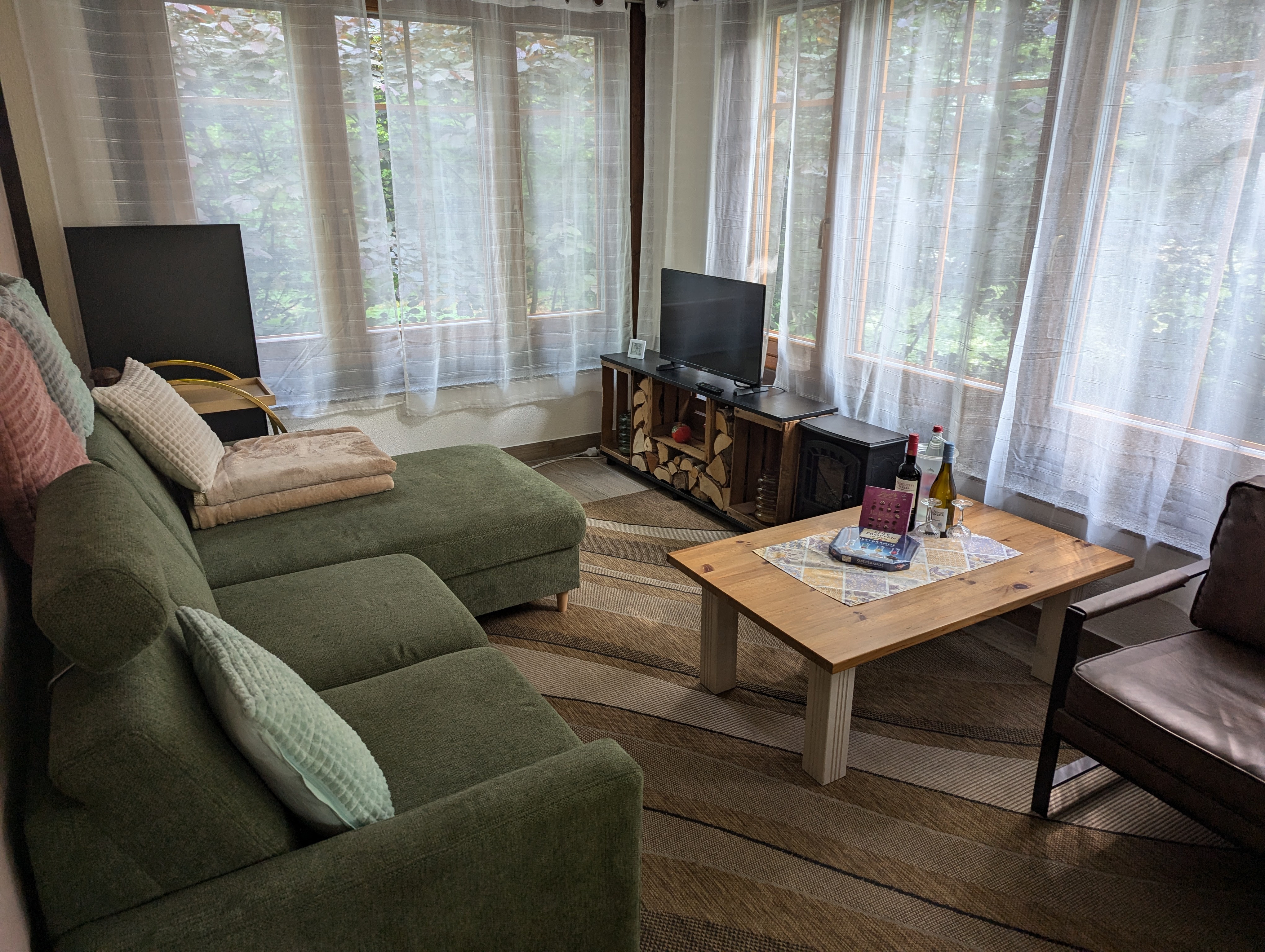 Waldnest – Wohnzimmer mit Sofa und Kaminofen