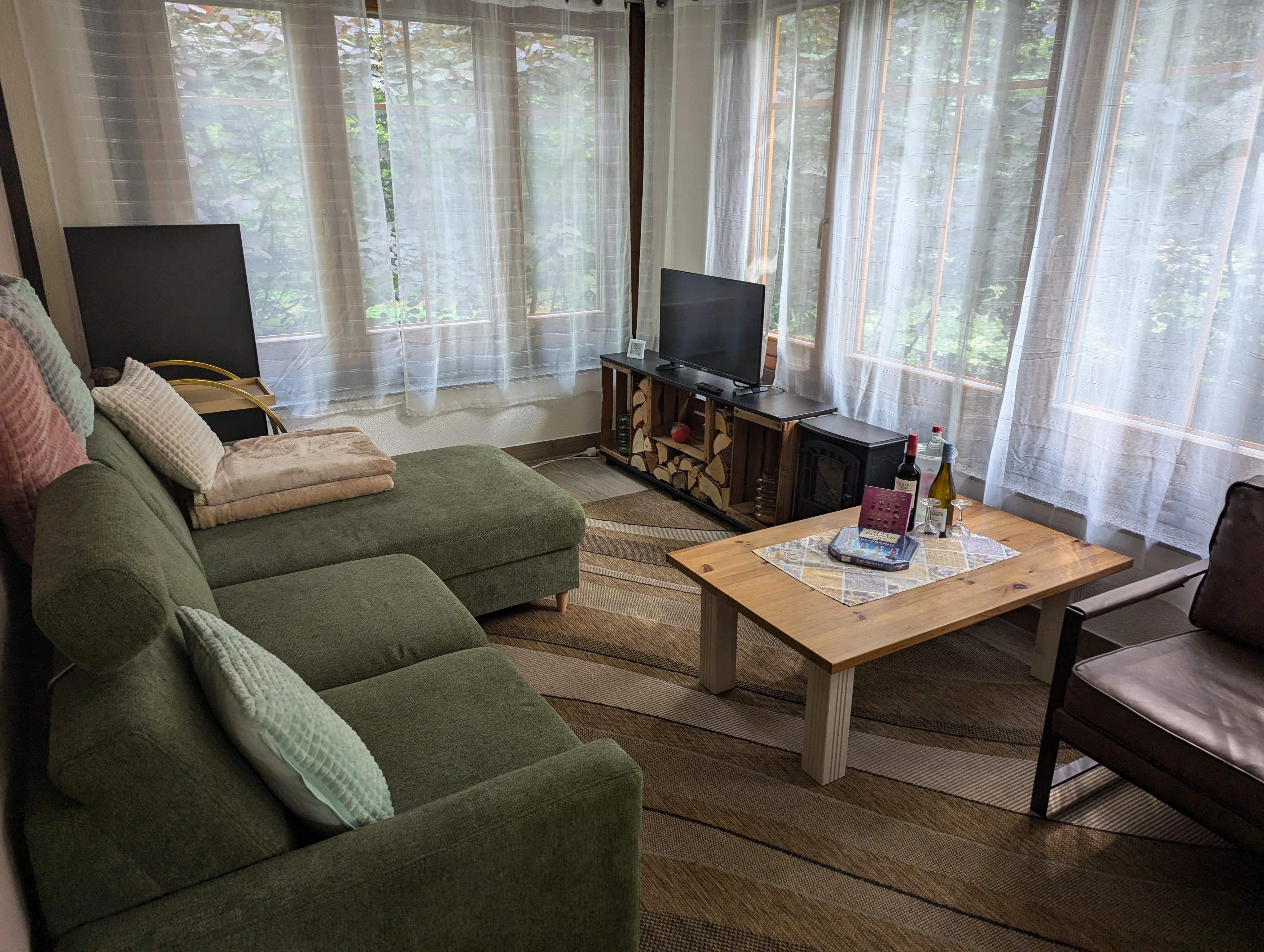 Waldnest – Wohnzimmer mit Sofa und Kaminofen